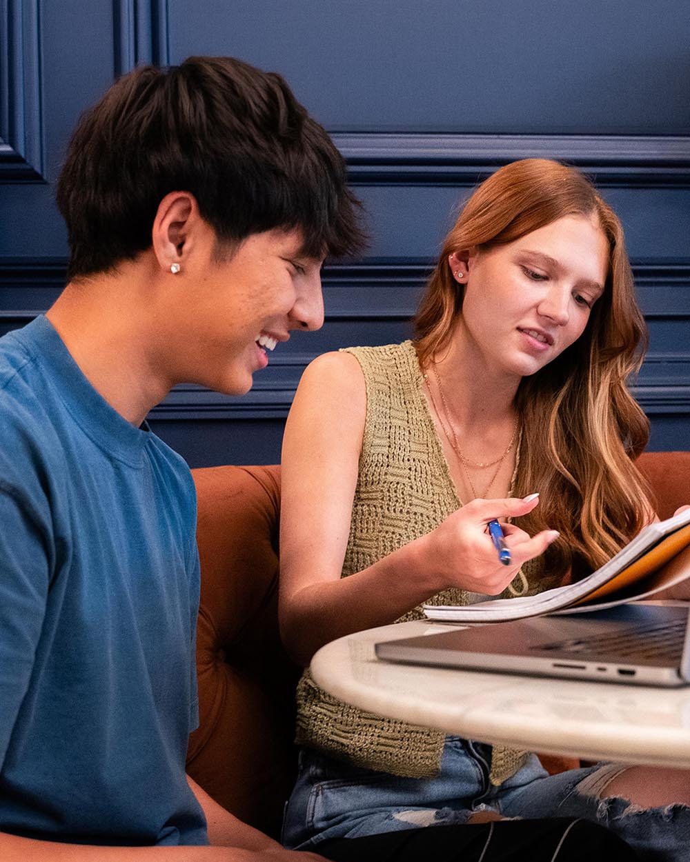 Two students reviewing notes over a laptop